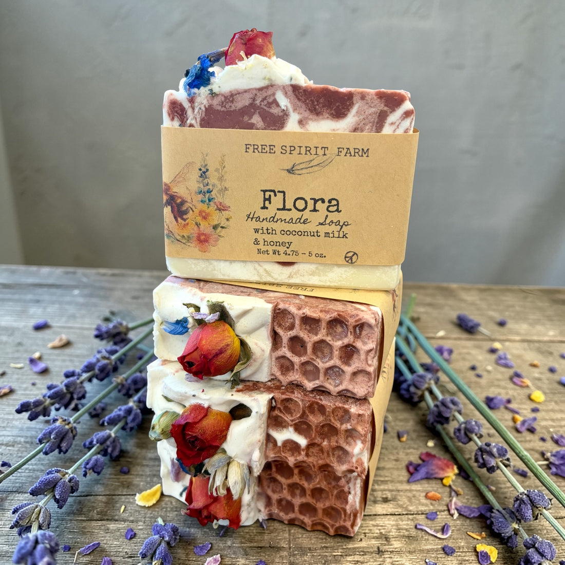 Stack of handmade soap bars with decorative elements on a wooden surface with lavender.