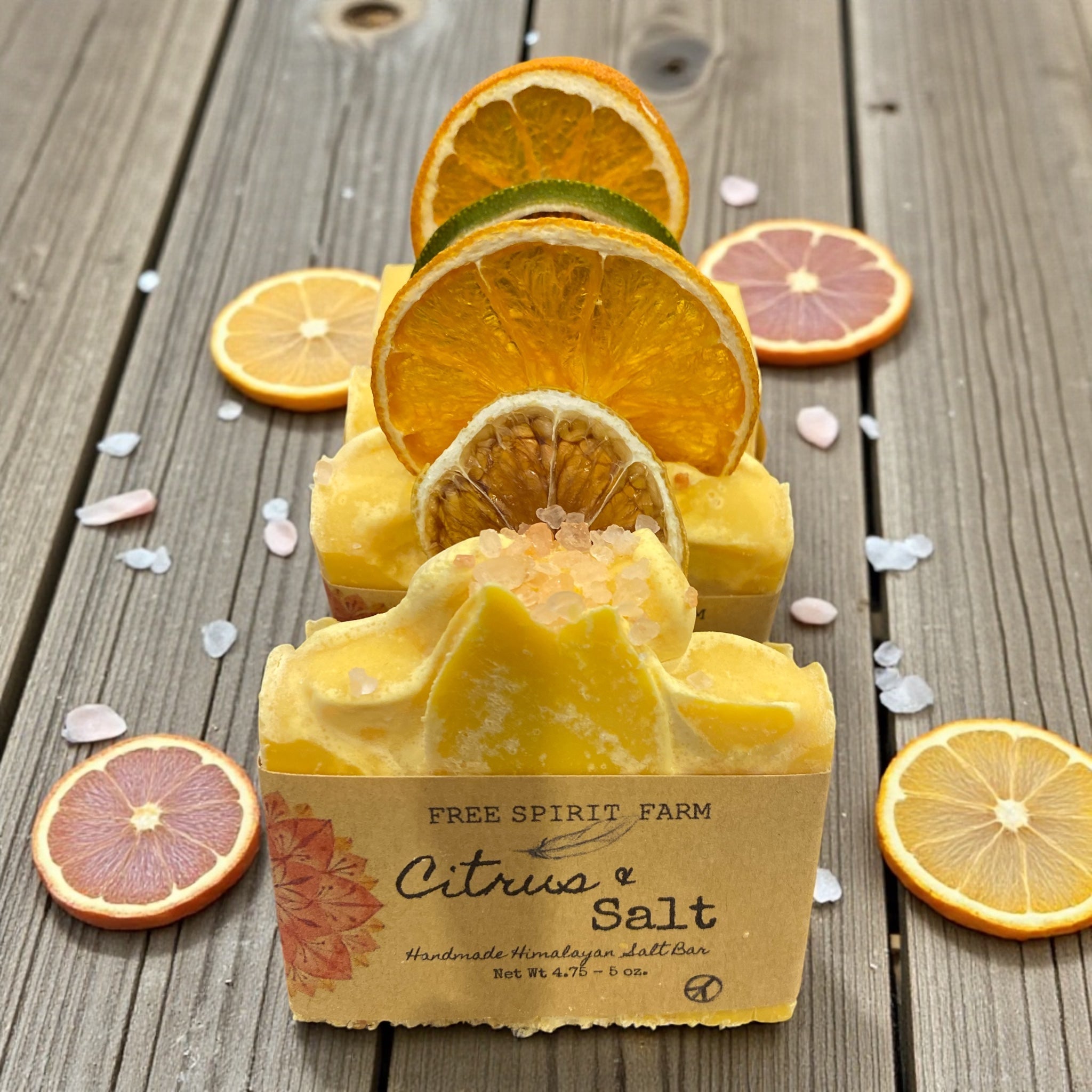 Citrus and salt soap bar with packaging on a wooden surface with orange slices.