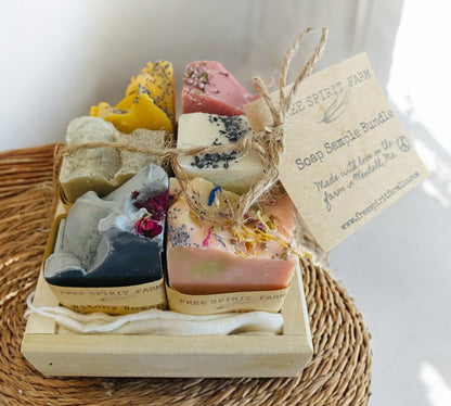 A bundle of various colored soaps tied with a string, placed in a wooden box with a name tag attached.
