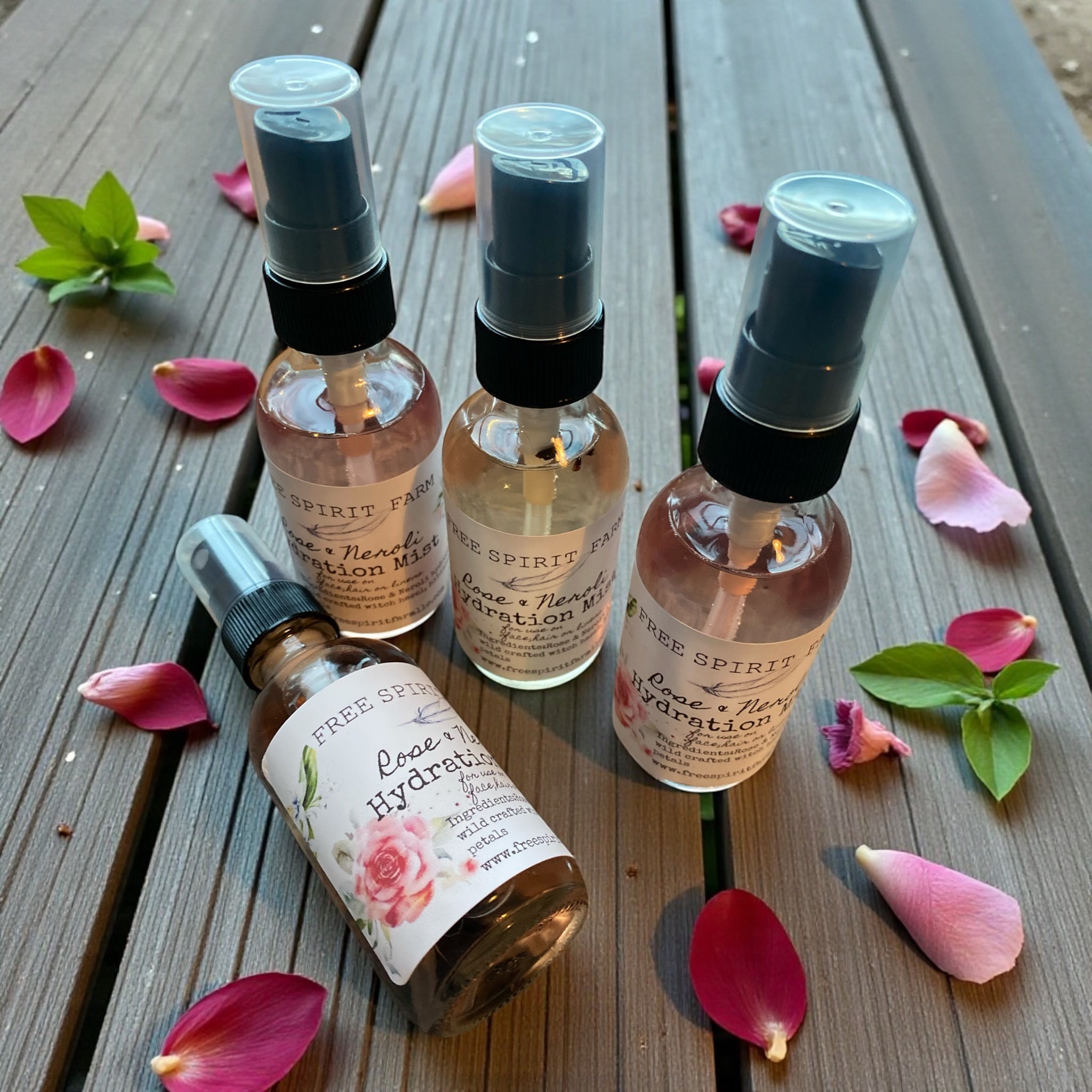 Five bottles of Free Spirits skincare products on a wooden surface with flowers.