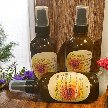 Three bottles of Free Spirit Farm Leave In Conditioner on a wooden surface with flowers in the background.