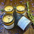 Three jars of Magnesium Tallow Lotion on a wooden surface with lavender flowers.