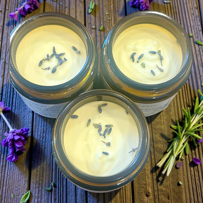 Three jars of Magnesium Tallow Lotion with lavender flowers on a wooden surface