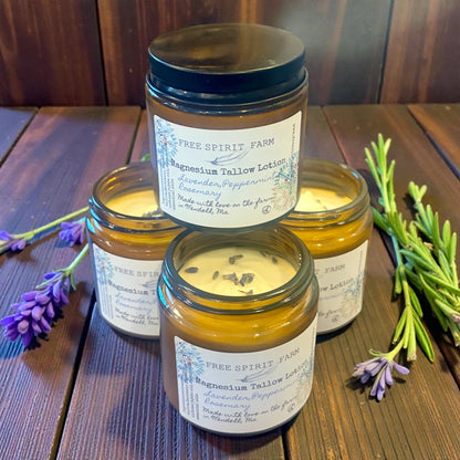 Jars of Free Spirit Farm magnesium tallow lotion on a wooden surface with lavender and rosemary.