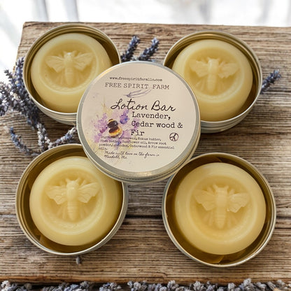 Four tins of Free Spirit Farm lotion bars on a wooden surface with lavender flowers.