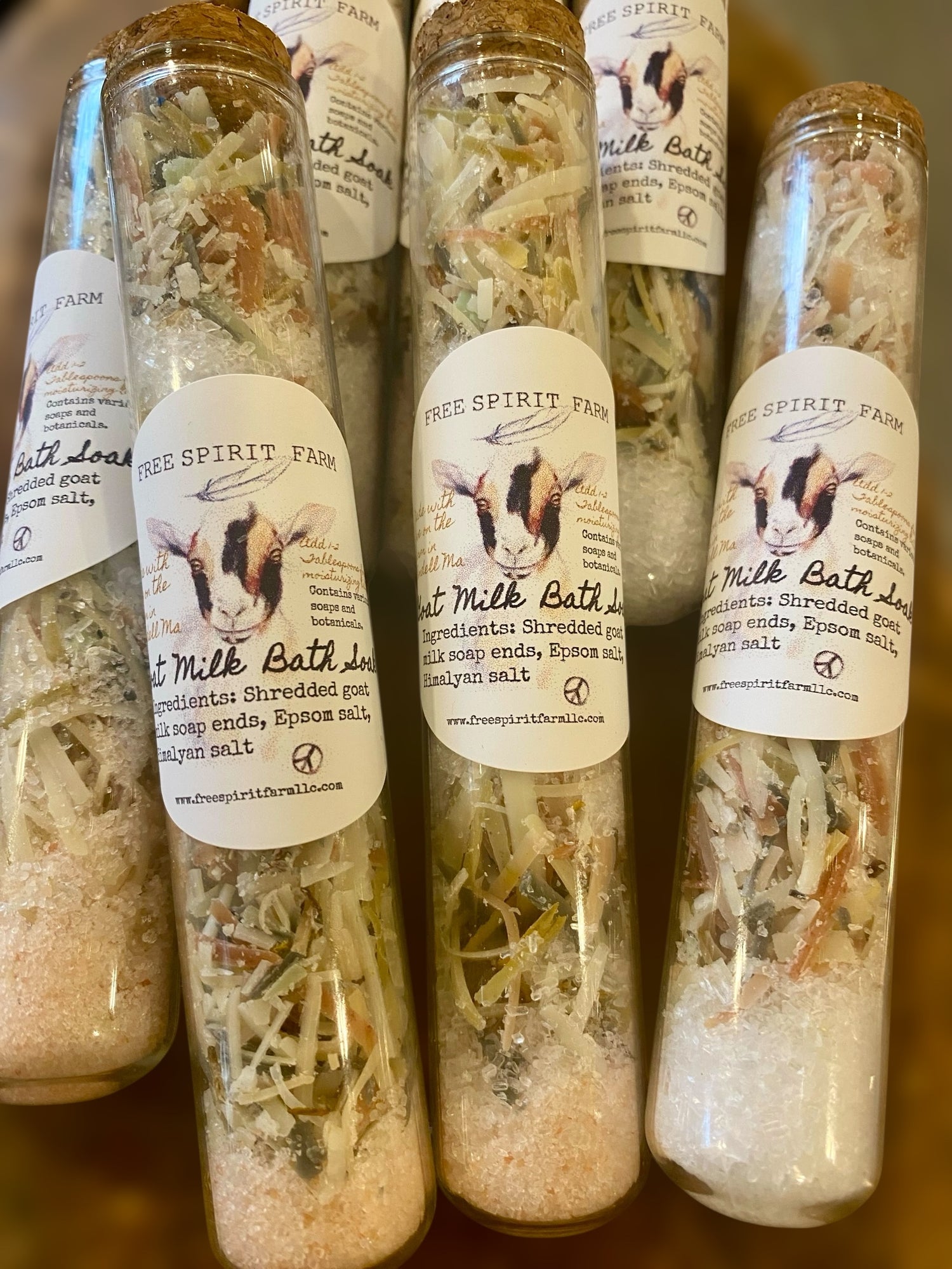 Bottles of Free Spirit Farm milk bath salts on a wooden surface
