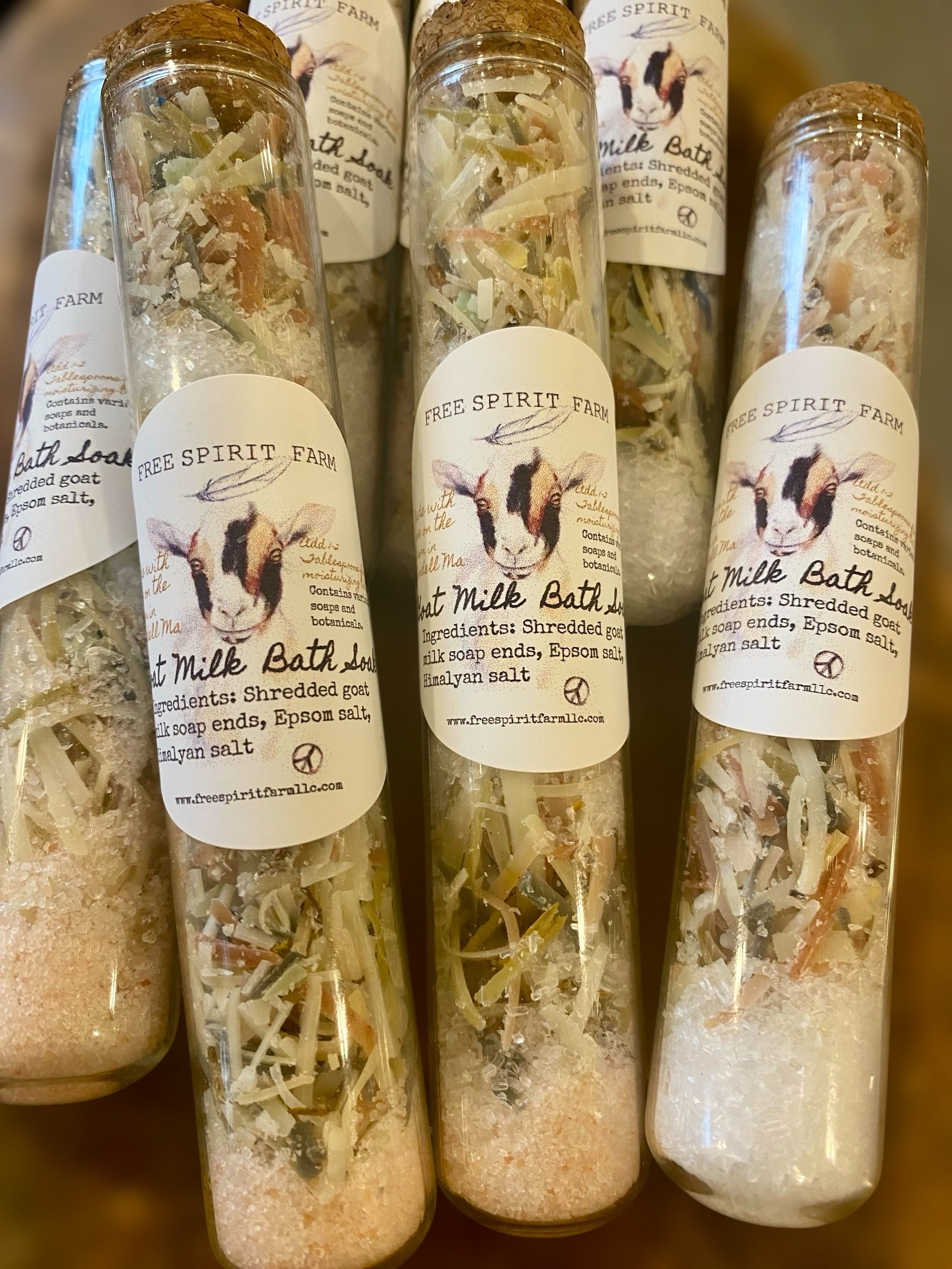 Bottles of Free Spirit Farm milk bath salts on a wooden surface
