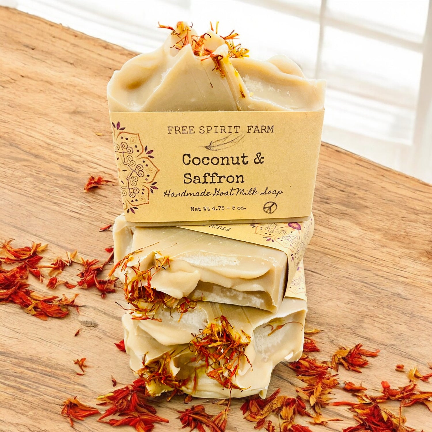 Stack of coconut and saffron soap bars with a Free Spirit Farm label on a wooden surface.