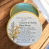 A tin container of Tallow & Tansy Face Balm with a label featuring illustrations of plants and text detailing the product&