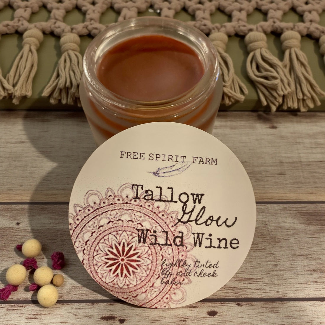 Jar of tallow balm with a label on a wooden surface, featuring &