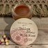 Jar of tallow balm with a label on a wooden surface, featuring &