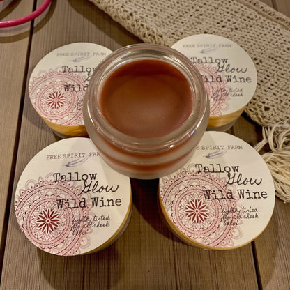 Jar of Tallow Glow Wild Wine balm with four containers labeled on a wooden surface.