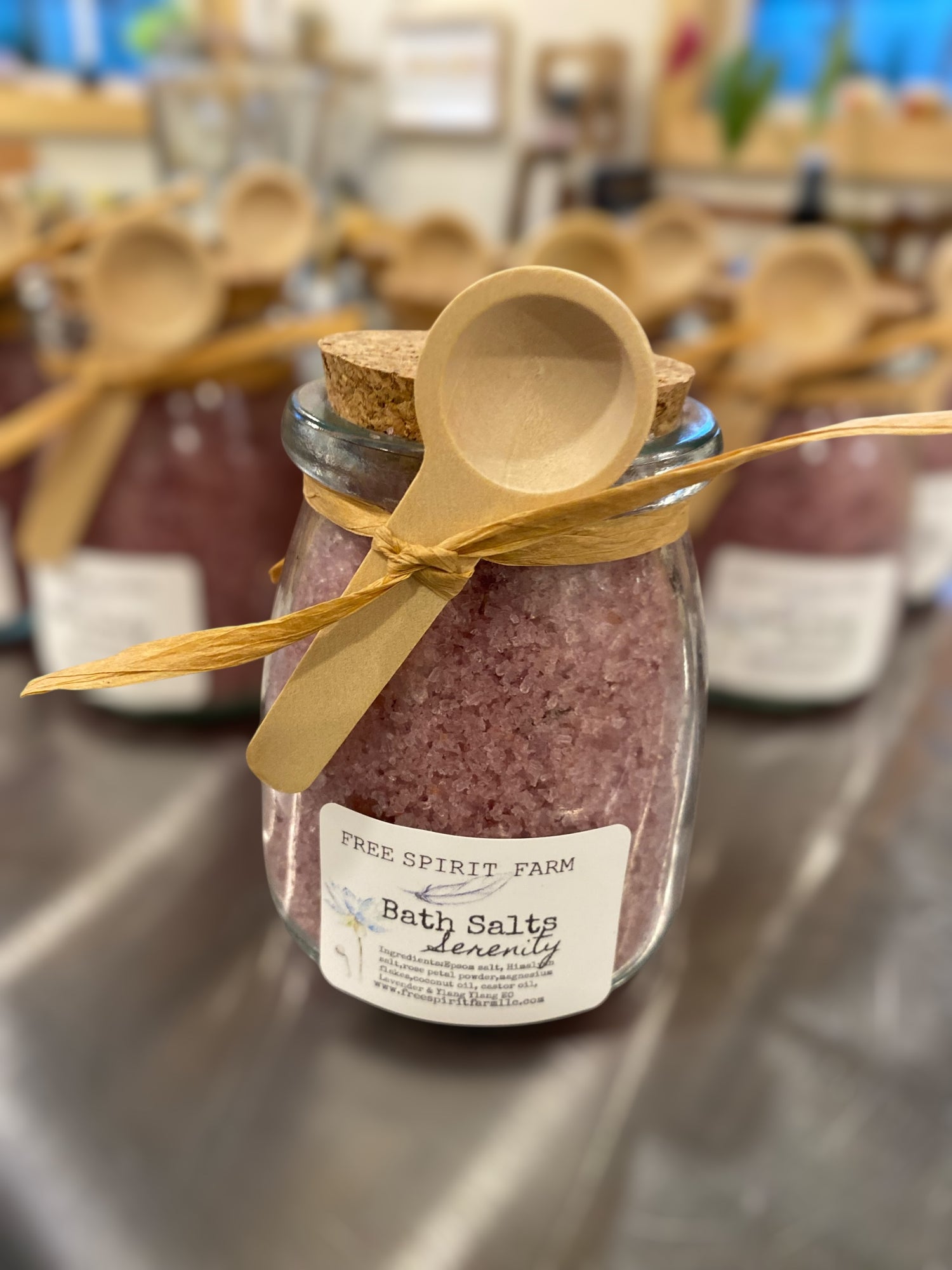 Jar of bath salts with a wooden spoon on a metal surface, labeled &