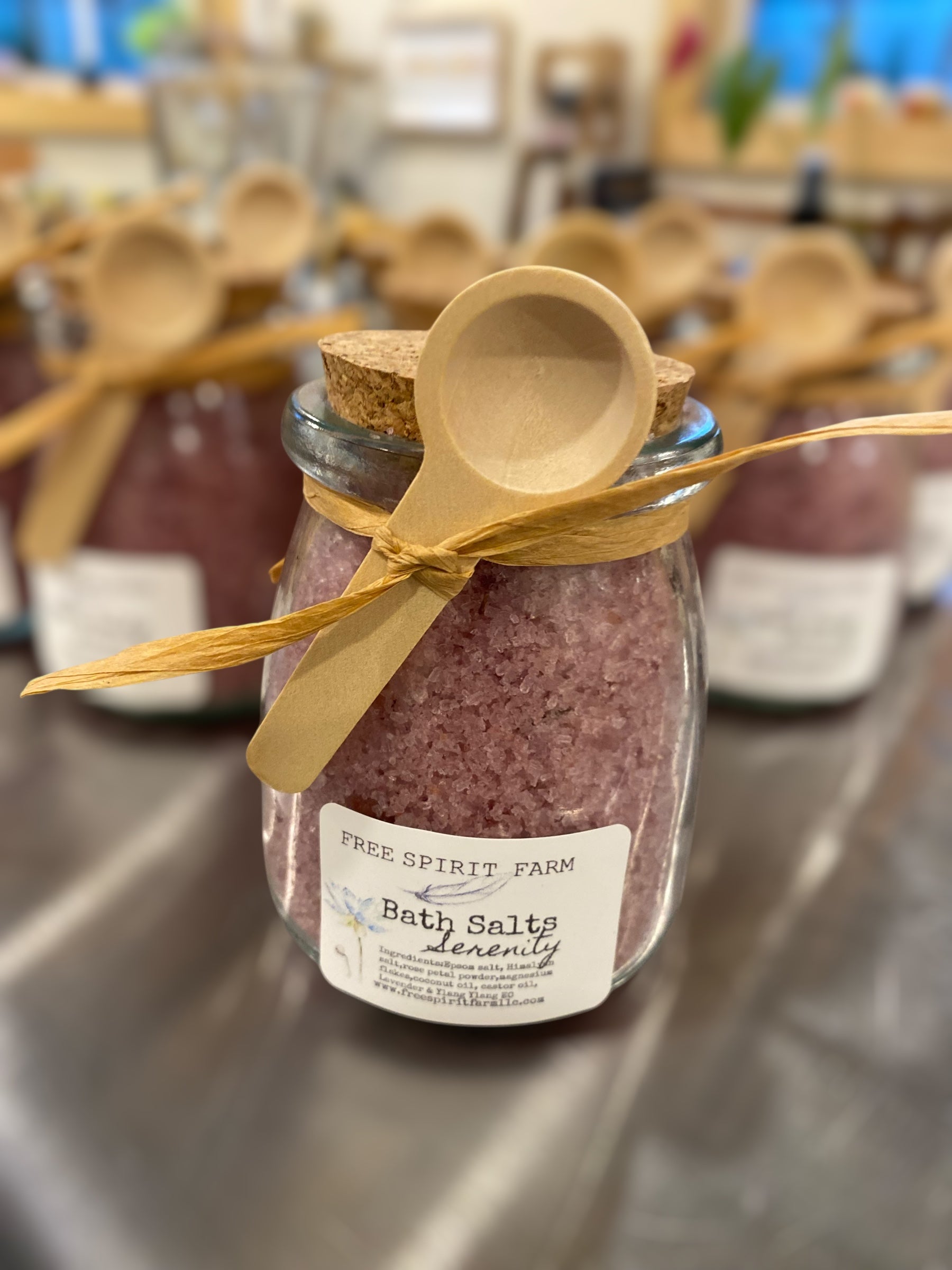 Jar of bath salts with a wooden spoon on a metal surface, labeled &