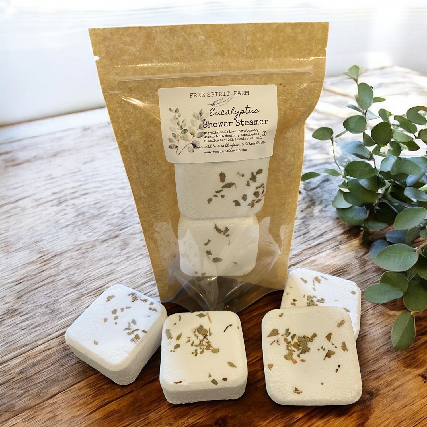 Eucalyptus shower steamer packaging with four steamer cubes on a wooden surface.