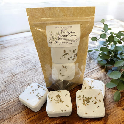 Eucalyptus shower steamer packaging with four steamer cubes on a wooden surface.