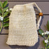 Beige mesh bag with a wooden handle on a wooden surface with green leaves and flowers.