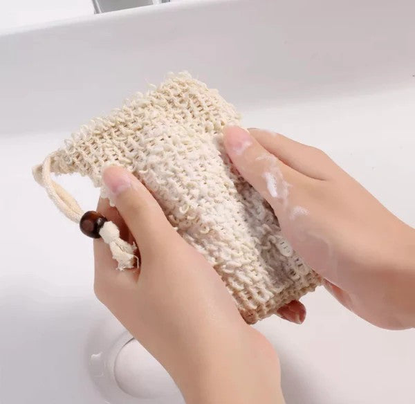 Hand holding a natural fiber soap dish with soap suds on a white background