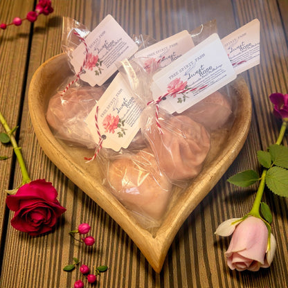 Heart-shaped dish with wrapped products and rose flowers on a wooden surface
