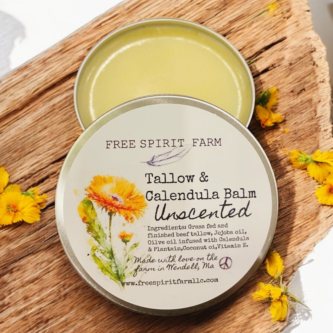 Tallow &amp; Calendula Balm container with label on a wooden surface surrounded by flowers