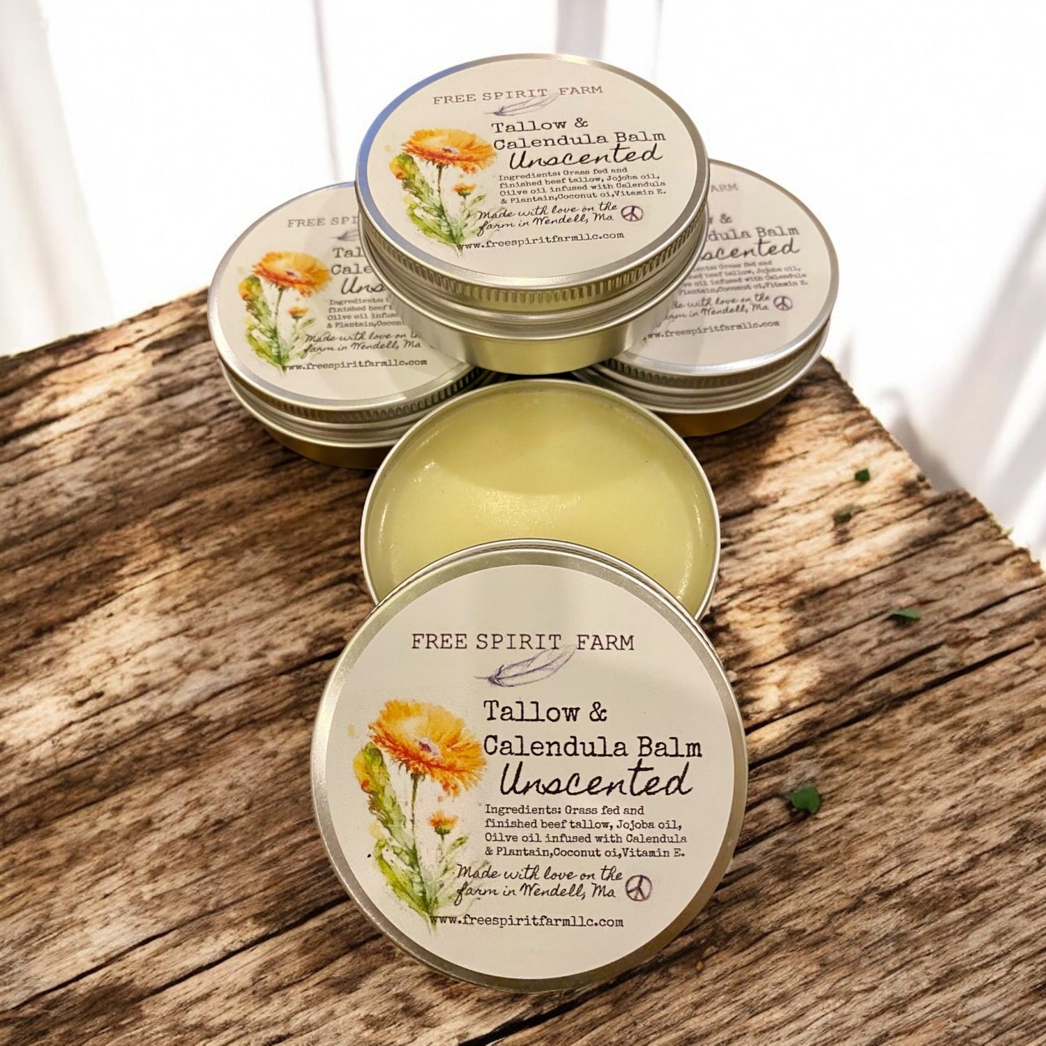 Tallow and calendula balm tins on a wooden surface with &