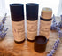Three tubes of Tallow Lip Balm in a cardboard recyclable packaging, with lavender plants in the background.