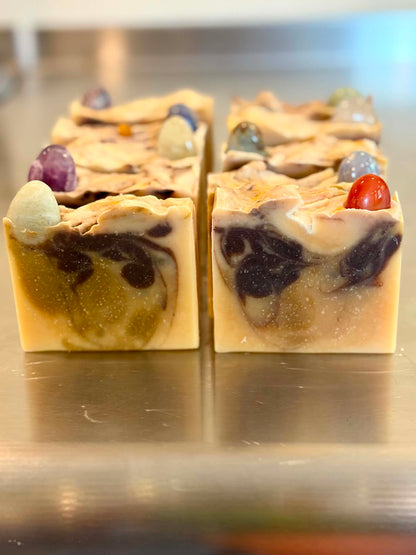 Free Spirit Farm bars of artisanal goat milk soap arranged on a reflective metallic surface. gem stone soap.