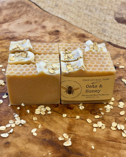 Two bars of soap with honeycomb and oatmeal design on a wooden surface, featuring &